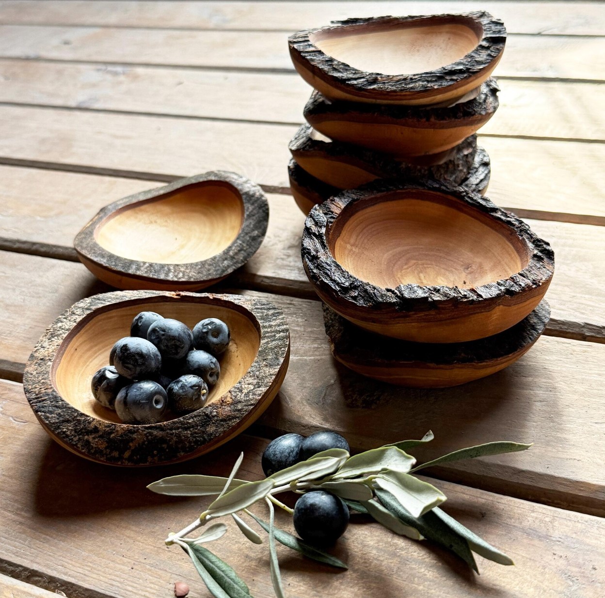 Small olive wood bowls with natural bark edges holding olives