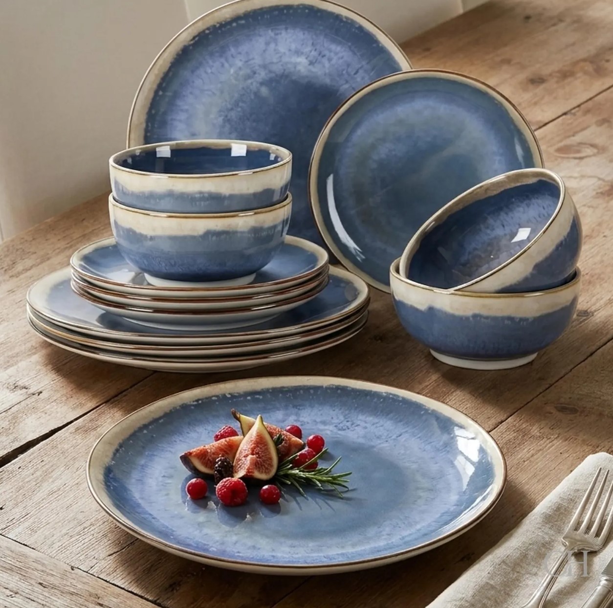Blue reactive glaze plates and bowls with cream rims on a rustic table